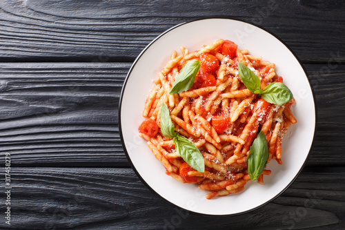 Pasta trofie recipe with tomato sauce, parmesan and basil close-up in a plate. Horizontal top view