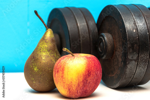 Healthy life concept - fruits and weights on a white floor