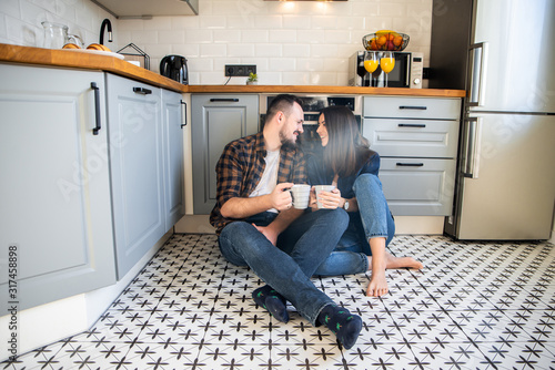 Happy couple sit on the floor with a cups