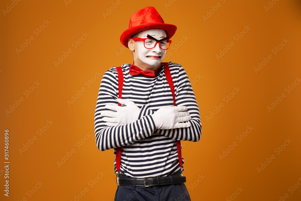 Frozen mime in red hat and striped t-shirt on blank orange background Frozen mime in red hat and striped t-shirt on blank orange background