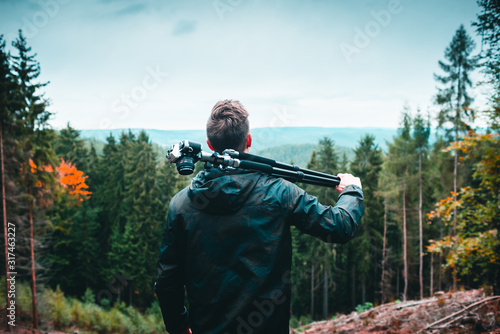 man with tripod and camera looking at a landscape photo