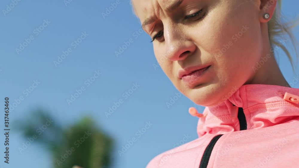 Handheld video shows of sporty woman using mobile phone. Shot with RED helium camera in Handheld video shows of sporty woman using mobile phone. Shot with RED helium camera in