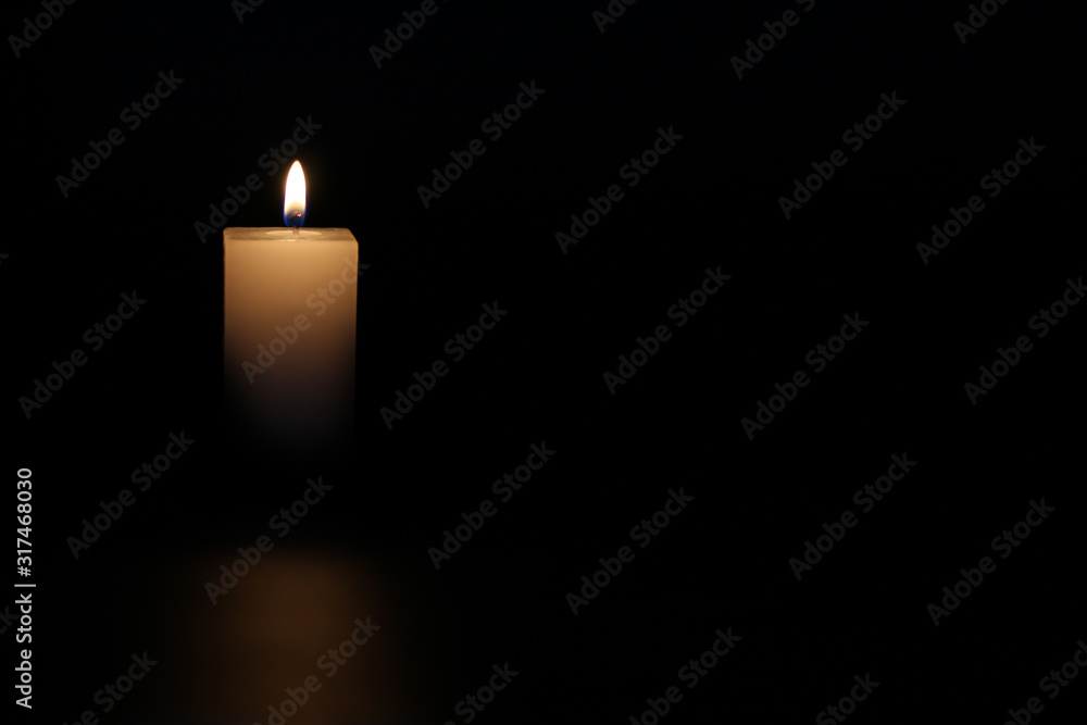 A lighted candle on a neutral black background, ideal for text application A lighted candle on a neutral black background, ideal for text application