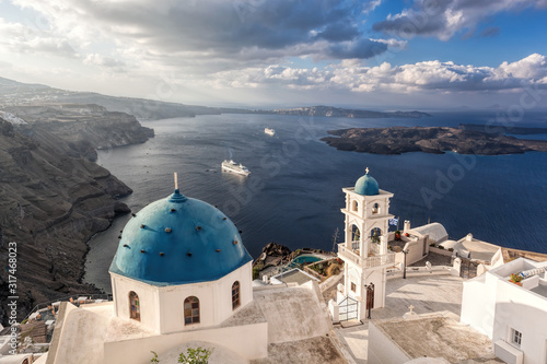 Thira on the Santorini island with famous churches against ships in Greece