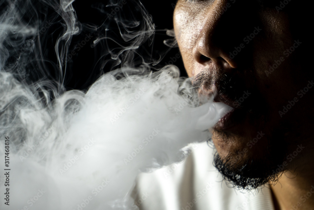 asian man smoked From cigarettes or electric cigarettes or marijuana In the black background