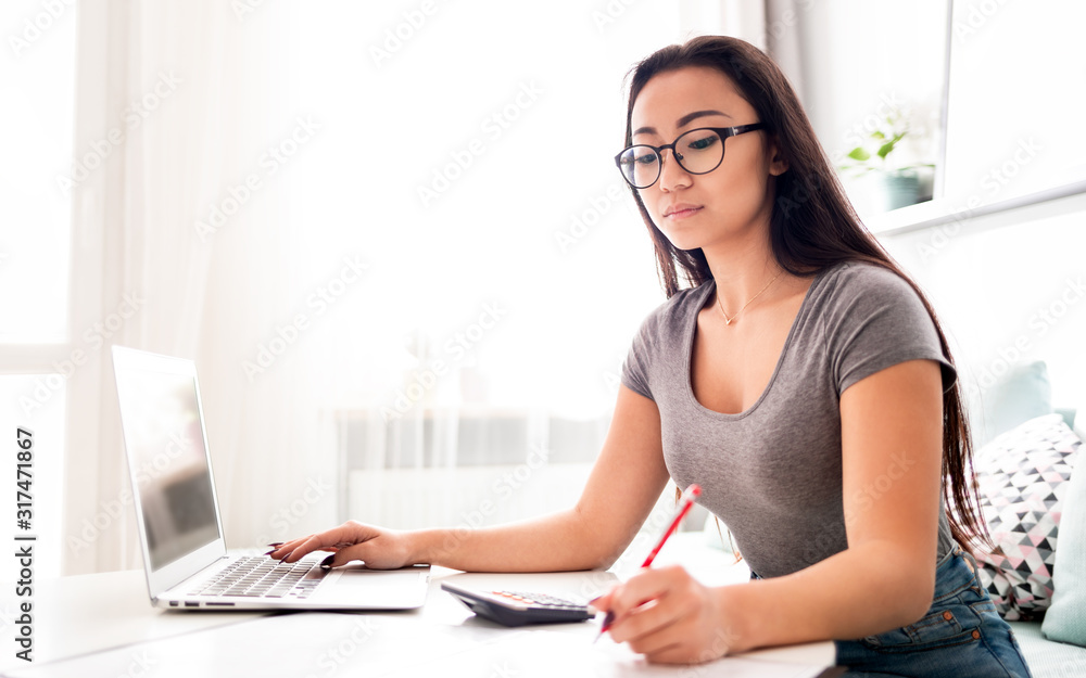 Asian woman using calculator and laptop for calaulating home budget finance taxes Asian woman using calculator and laptop for calaulating home budget finance taxes