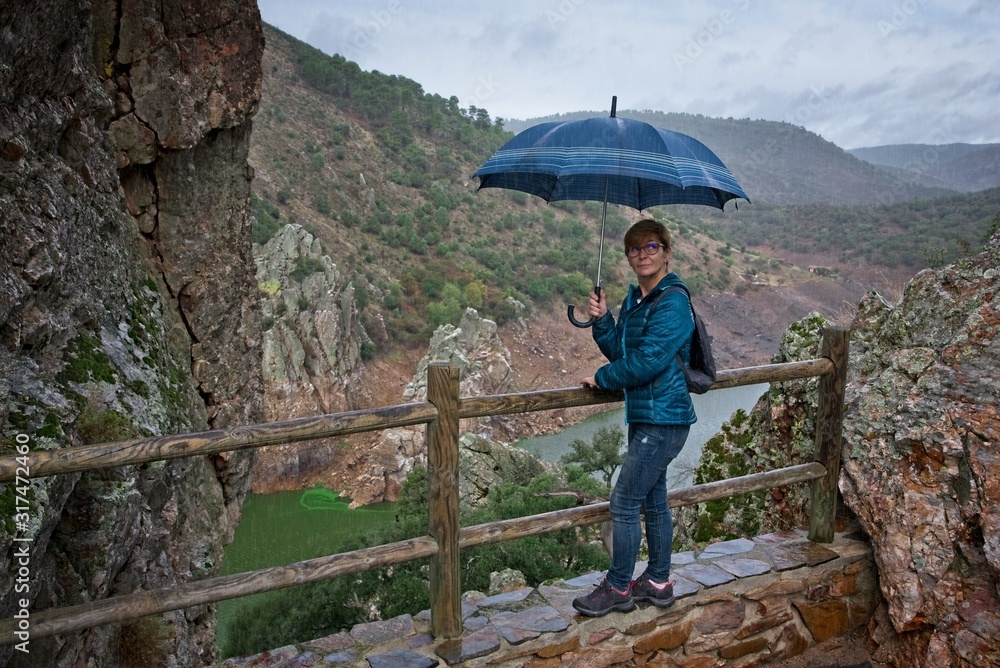 A woman with umbrella on a rainy day in a national park of Spain