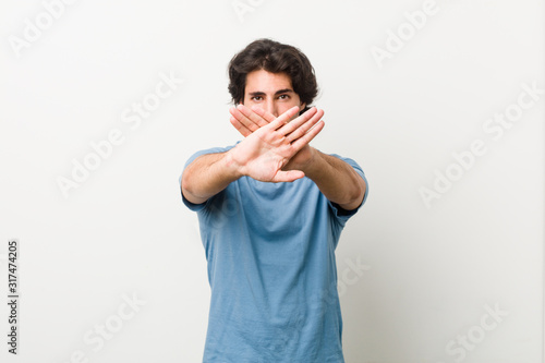 Young handsome man against a white background doing a denial gesture