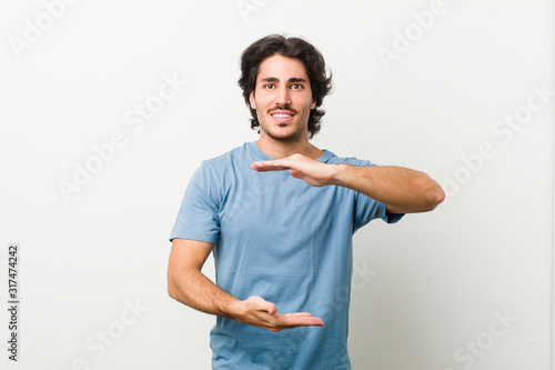 Young handsome man against a white background holding something with both hands, product presentation.