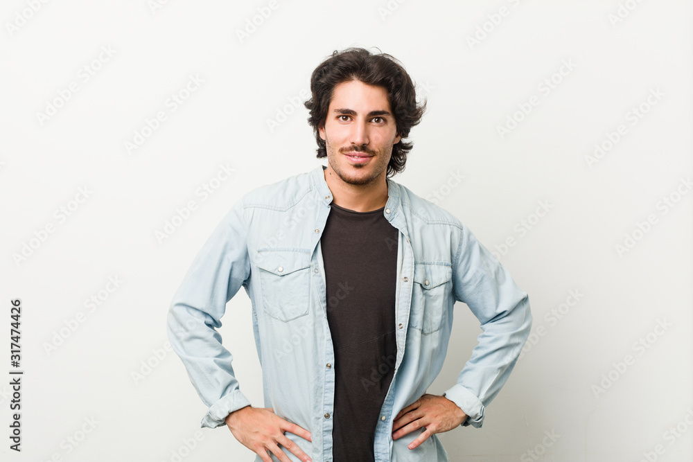 Young handsome man against a white background confident keeping hands on hips. Young handsome man against a white background confident keeping hands on hips.