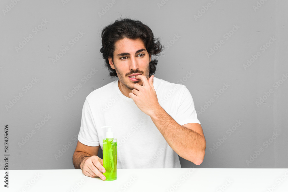Young man holding an aloe vera bottle relaxed thinking about something looking at a copy space. Young man holding an aloe vera bottle relaxed thinking about something looking at a copy space.