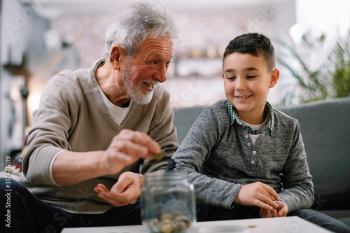 Grandpa and grandson saving money. Grandfather teaching grandchild how to save money. 