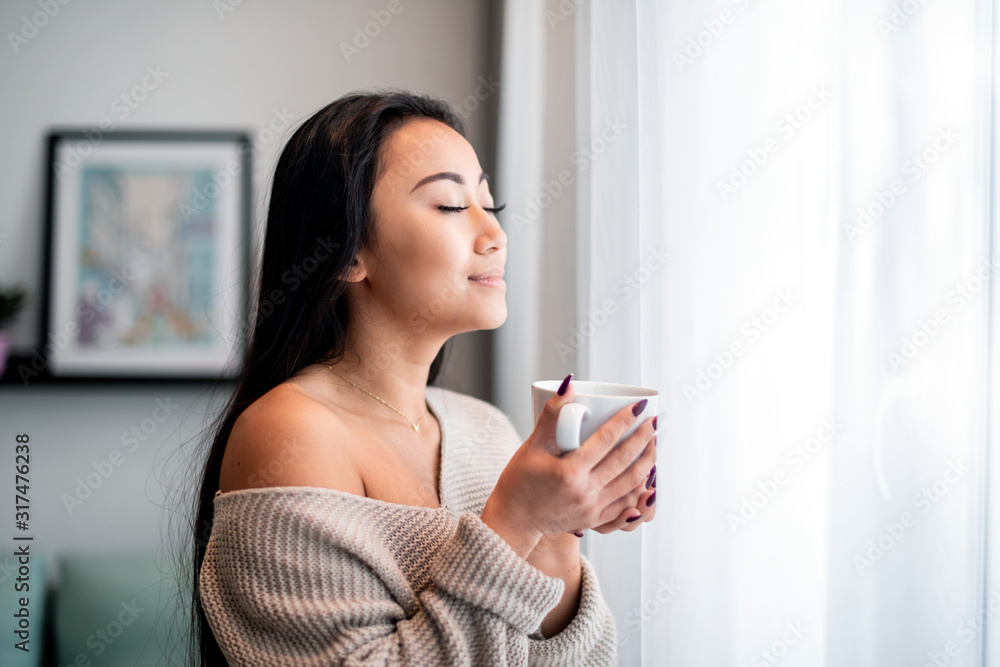 Relaxed asian woman with cup of tea or coffee spending leisure time at home Relaxed asian woman with cup of tea or coffee spending leisure time at home