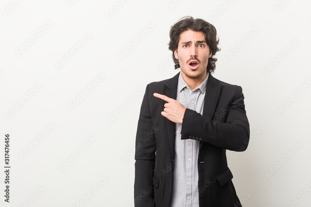 Young business man against a white background pointing to the side Young business man against a white background pointing to the side