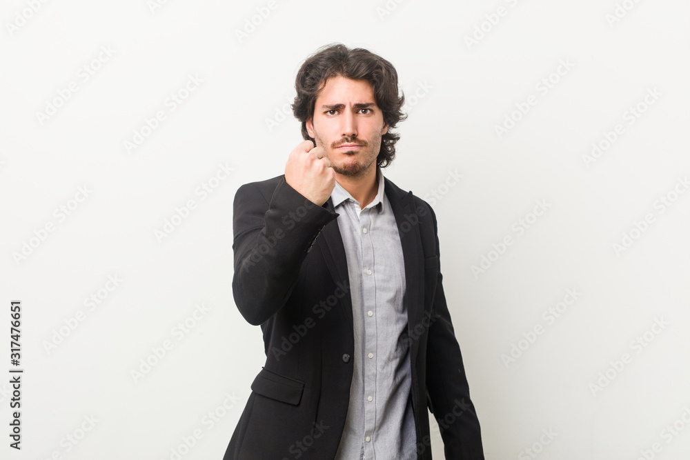 Young business man against a white background showing fist to camera, aggressive facial expression. Young business man against a white background showing fist to camera, aggressive facial expression.