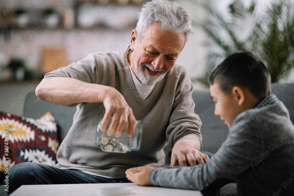 Obraz premium Grandpa and grandson saving money. Grandfather teaching grandchild how to save money. 