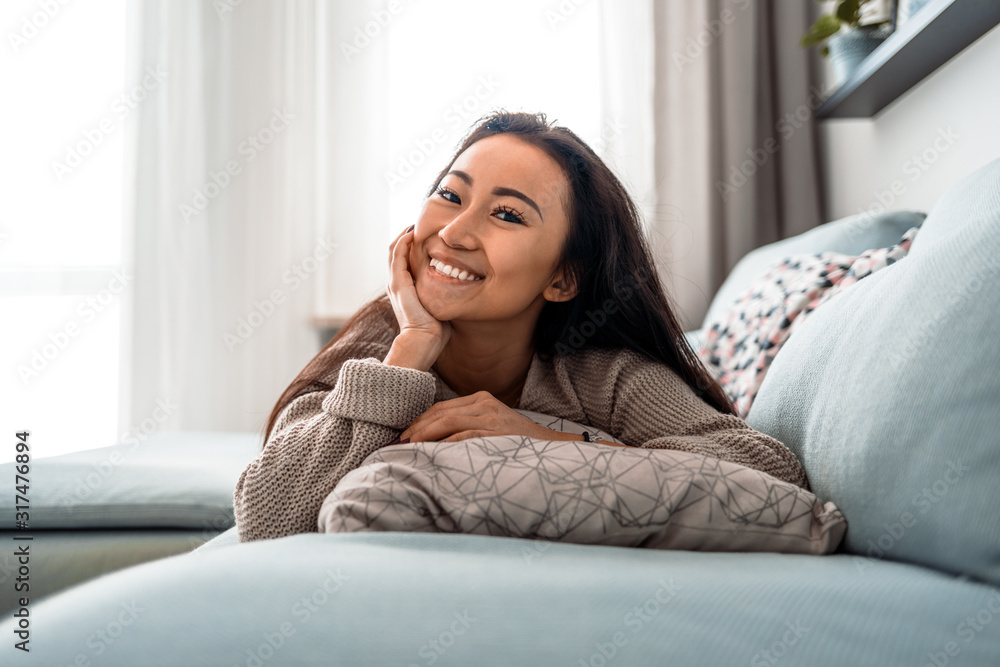 Relaxed smiling asian woman sitting on sofa at home Relaxed smiling asian woman sitting on sofa at home