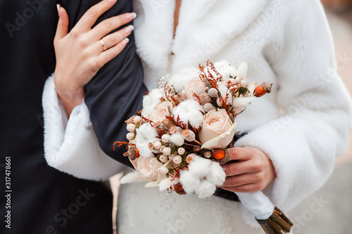 winter wedding bouquet of cotton and delicate roses. Bouquet in the hands of the newlyweds
