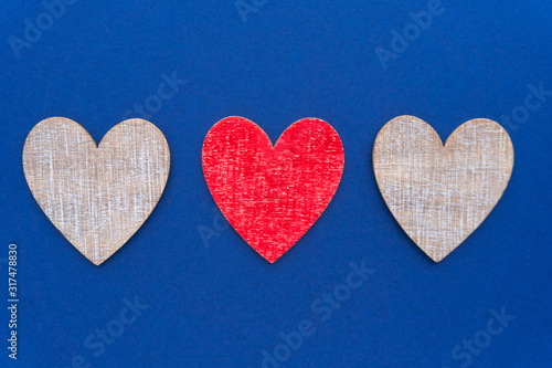 Valentine day background. Flat lay with three wooden hearts at classic blue background.
