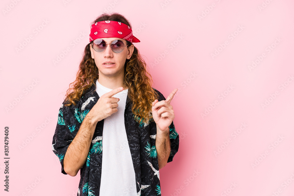 Young hippie caucasian man isolated shocked pointing with index fingers to a copy space. Young hippie caucasian man isolated shocked pointing with index fingers to a copy space.