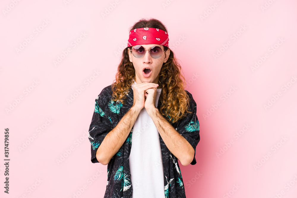 Young hippie caucasian man isolated praying for luck, amazed and opening mouth looking to front.