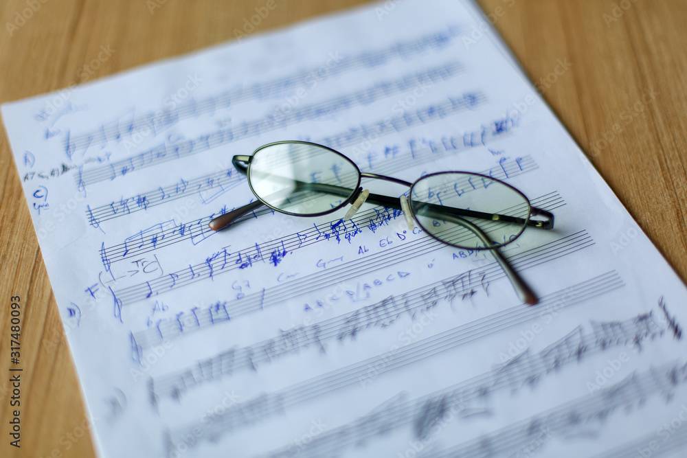 musical manuscript with notes, glasses in the background musical manuscript with notes, glasses in the background