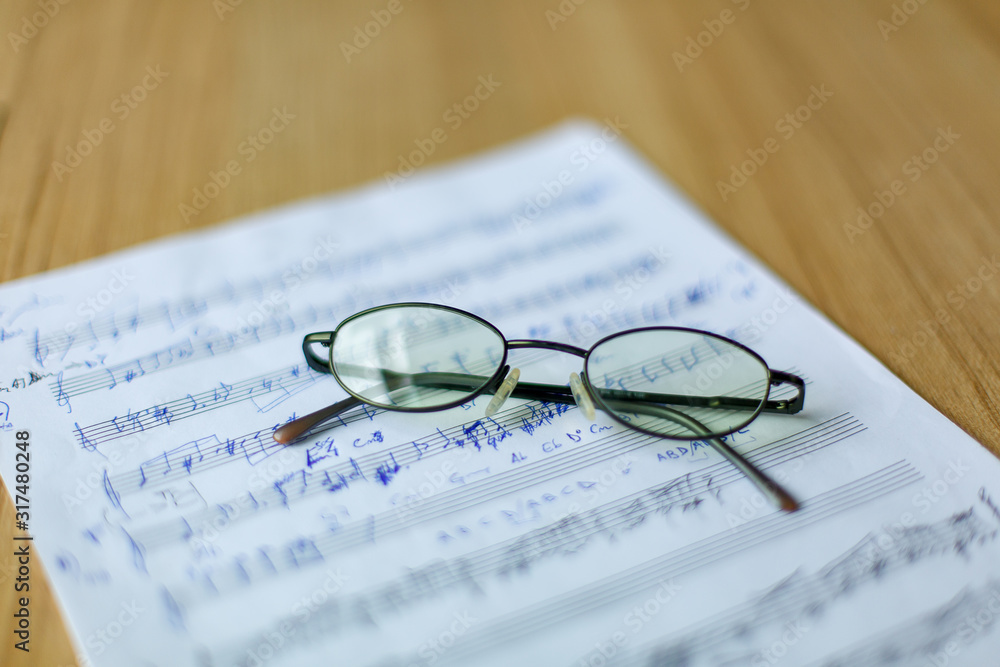 musical manuscript with notes, glasses in the background musical manuscript with notes, glasses in the background