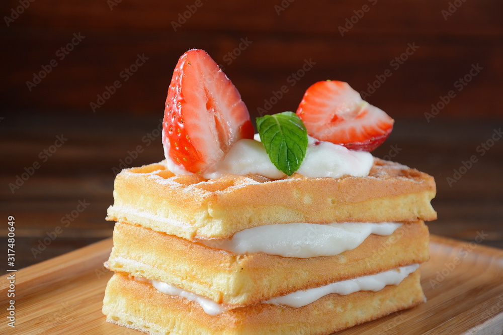 Belgian waffles with strawberries, whipped cream and mint leaves. Tasty dessert concept