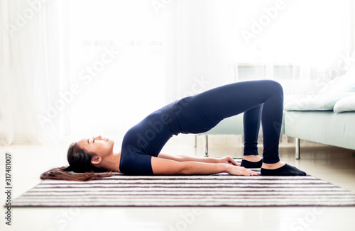 Young asian girl exercising at home on carpet in living room