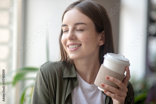 Smiling woman having a pleasure while drinking morning coffee