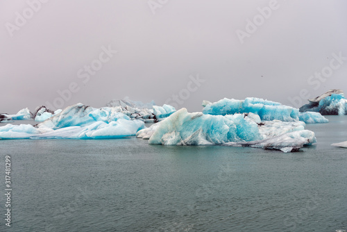 Blue colored melting icebergs floating around in Jokulsarlon glacier lagoon in Iceland during foggy weather. Icelandic and traveling concept. To illustrate global warming and pollution. © Jon Anders Wiken