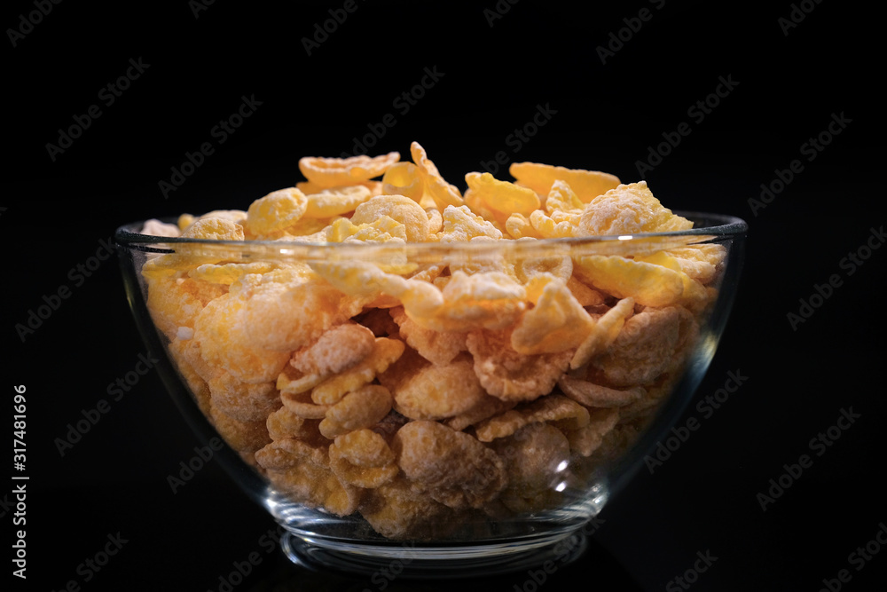 Cornflakes in a glass plate on a black background. Cornflakes in a glass plate on a black background.