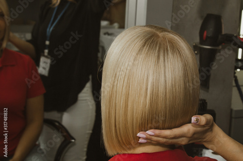 Closeup of a hairdresser cuts wet white hair of a client in a salon. Hairdresser cuts a woman. Side view of a hand cutting hair with scissors.