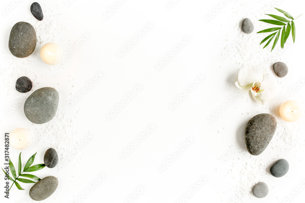 Spa stones, palm leaves, flower white orchid, candle and zen like grey stones on white background. Flat lay, top view - obrazy, fototapety, plakaty 