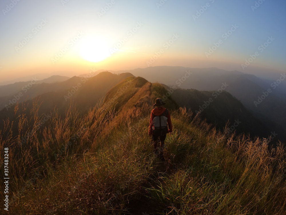Backpacker over the mountain at sunset