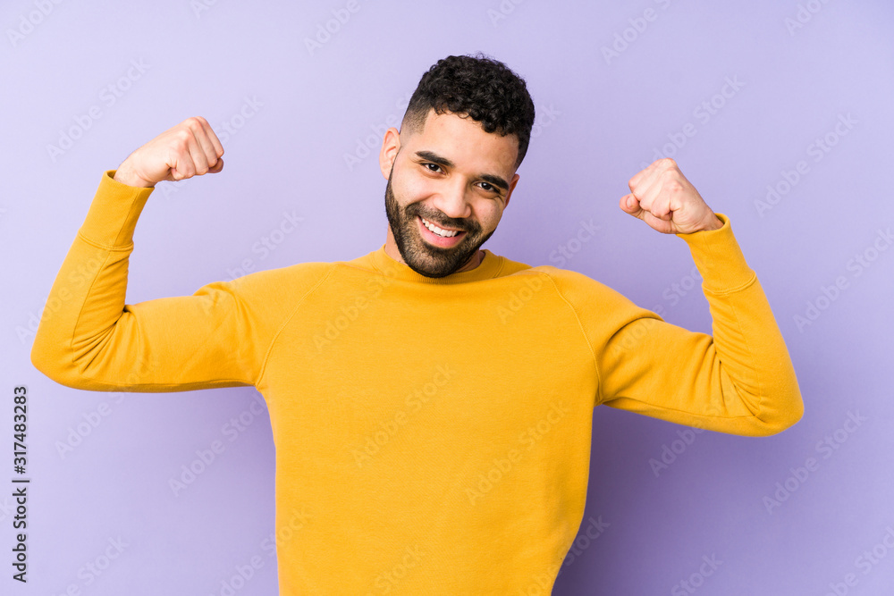 Young mixed race arabic man isolated showing strength gesture with arms, symbol of feminine power Young mixed race arabic man isolated showing strength gesture with arms, symbol of feminine power