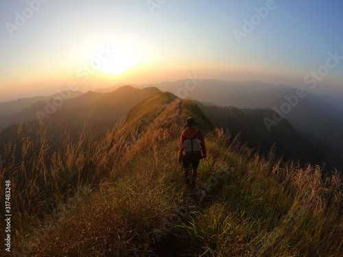 Backpacker over the mountain at sunset