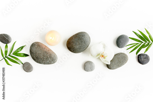 Canvas Print Spa stones, palm leaves, flower white orchid, candle and zen like grey stones on white background