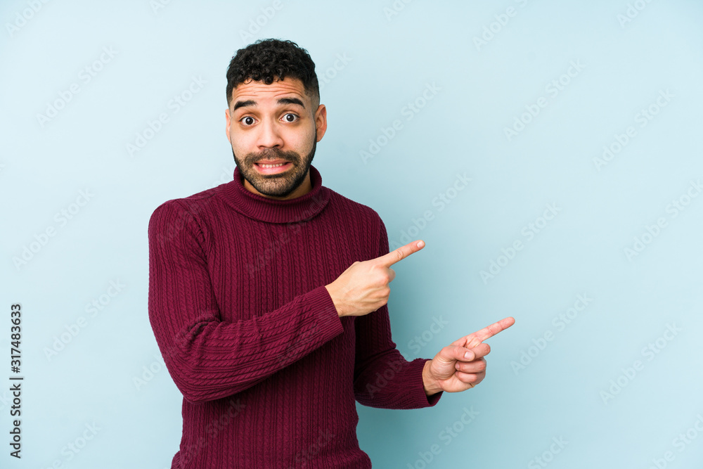 Young mixed race arabic man isolated shocked pointing with index fingers to a copy space. Young mixed race arabic man isolated shocked pointing with index fingers to a copy space.