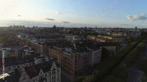 Drone shot flying over rooftops of Stockholm. Aerial view of Östermalm district at sunset. Oscar's Church (Oscarskyrkan), apartment buildings and street. Capital city of Sweden, cityscape skyline photo