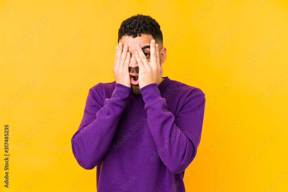 Young mixed race arabic man isolated blink through fingers frightened and nervous. Young mixed race arabic man isolated blink through fingers frightened and nervous.