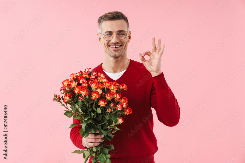Portrait of handsome caucasian man holding flowers and showing ok sign Portrait of handsome caucasian man holding flowers and showing ok sign