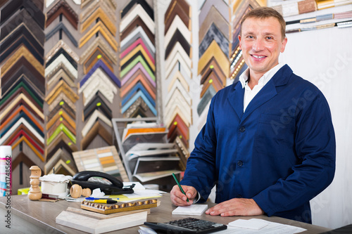 Konstfotografi concentrated man seller in picture framing studio with wooden details