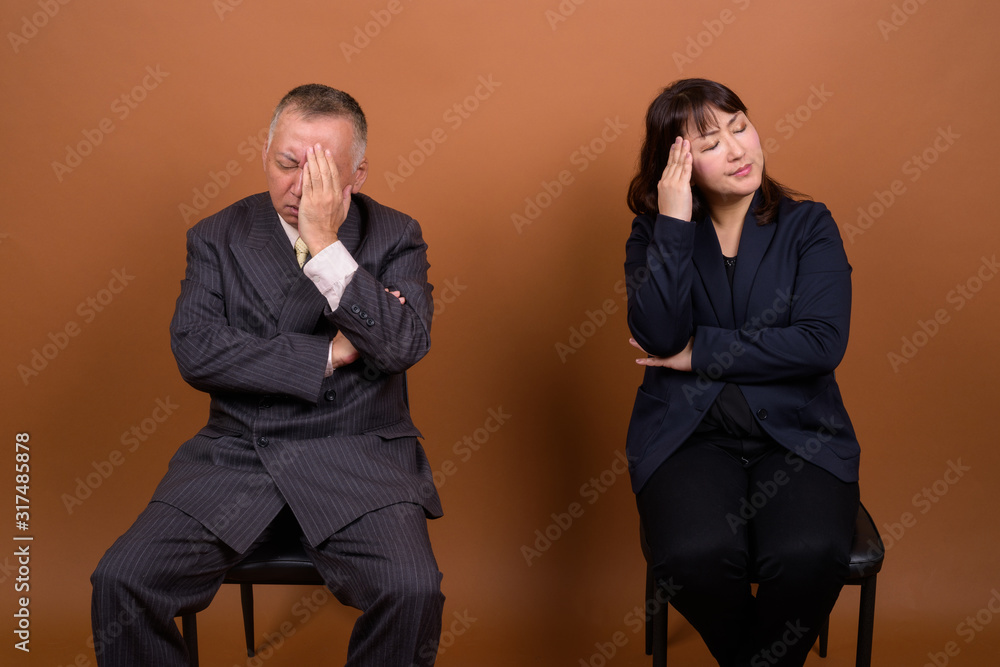 Obraz premium Mature Asian businessman and mature Asian businesswoman thinking together