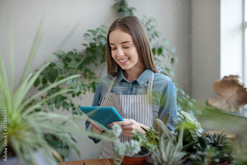 Smiling woman wearing apron taking care of plants Smiling woman wearing apron taking care of plants