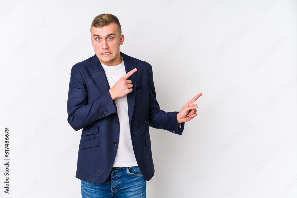 Young business caucasian man shocked pointing with index fingers to a copy space. Young business caucasian man shocked pointing with index fingers to a copy space.