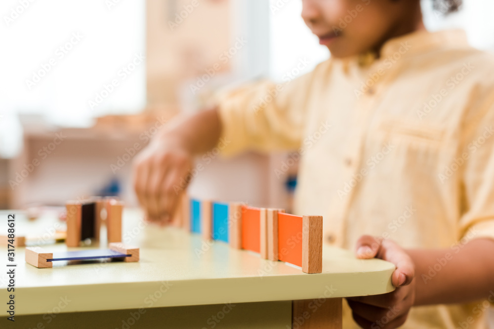 Selective focus of kid playing educational game in montessori school, cropped view Selective focus of kid playing educational game in montessori school, cropped view