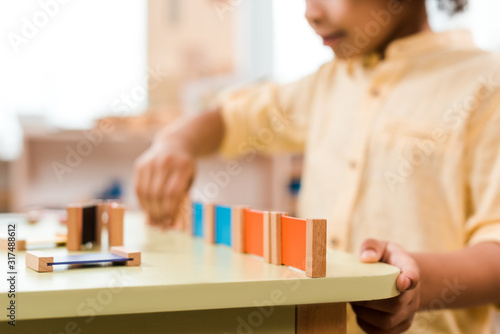Selective focus of kid playing educational game in montessori school, cropped view