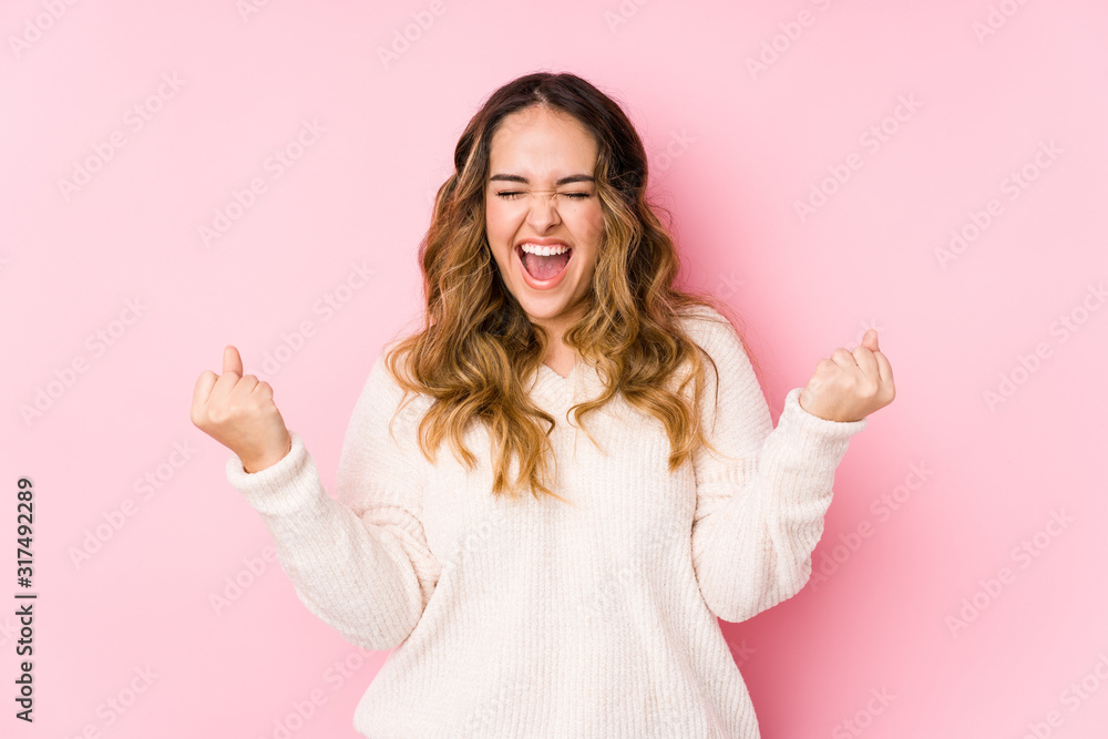 Young curvy woman posing in a pink background isolated cheering carefree and excited. Victory concept. Young curvy woman posing in a pink background isolated cheering carefree and excited. Victory concept.