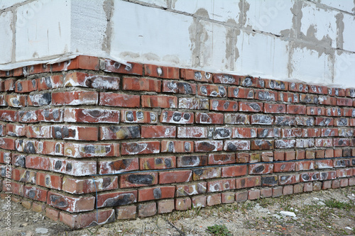Mineral efflorescence on brick house foundation wall. Efflorescence salt as an indicator of moisture problems in house building construction